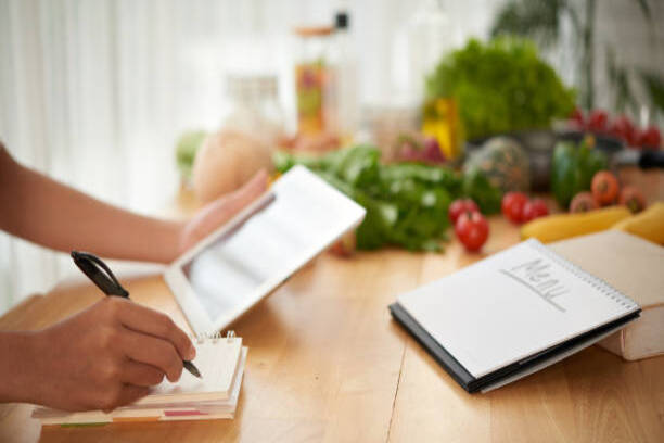 Hands of woman composing healthy menu for upcoming week